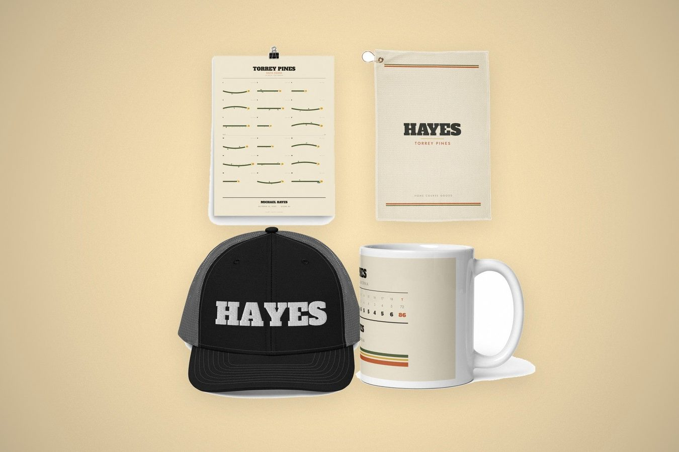 A personalized golf gift set laid out on cream: a course map print, a golf towel and an embroidered trucker hat with the same name, and a scorecard mug